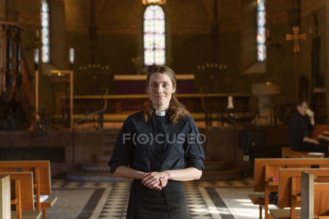Portrait de prêtre debout et regardant la caméra dans l'église — Photo de stock