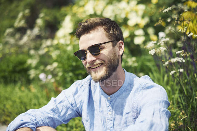Smiling mid adult man in sunglasses by flowers — Stock Photo