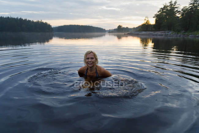 Femme dans le lac Skiren au coucher du soleil en Suède — Photo de stock