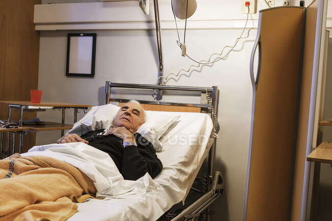 Uomo anziano sdraiato sul letto d'ospedale — Foto stock