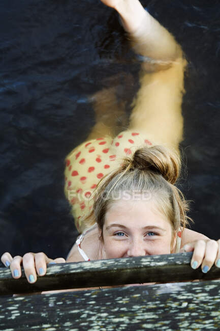 Vista de gran angular de una chica adolescente feliz y guapa nadando en el mar y sonriendo a cámara. - foto de stock