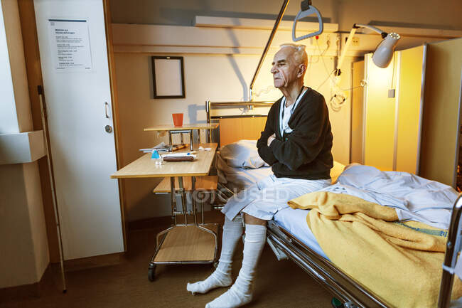 Senior man sitting on hospital bed — Stock Photo
