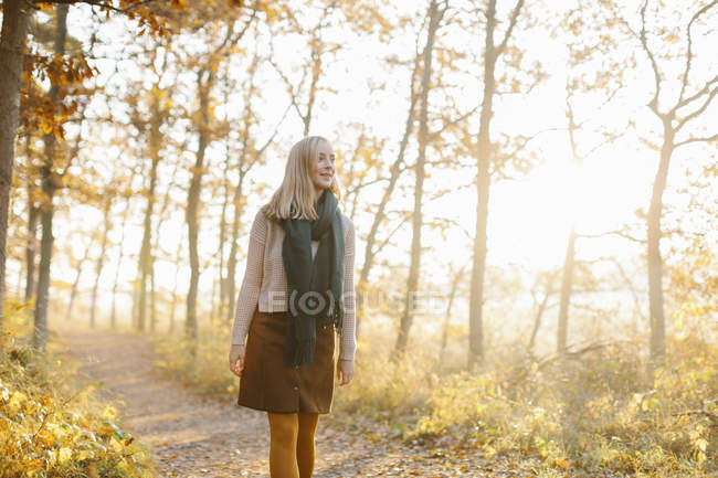 Mujer caminando en bosque otoñal - foto de stock
