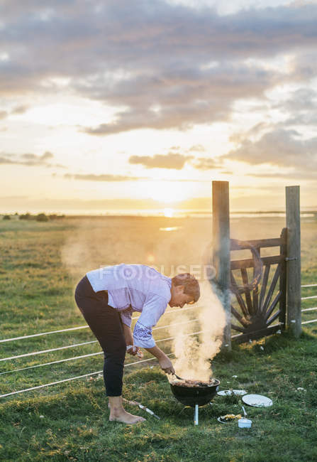 Woman cooking with brazier in field — Stock Photo