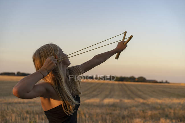 Teenage girl using sling shot in field — Stock Photo