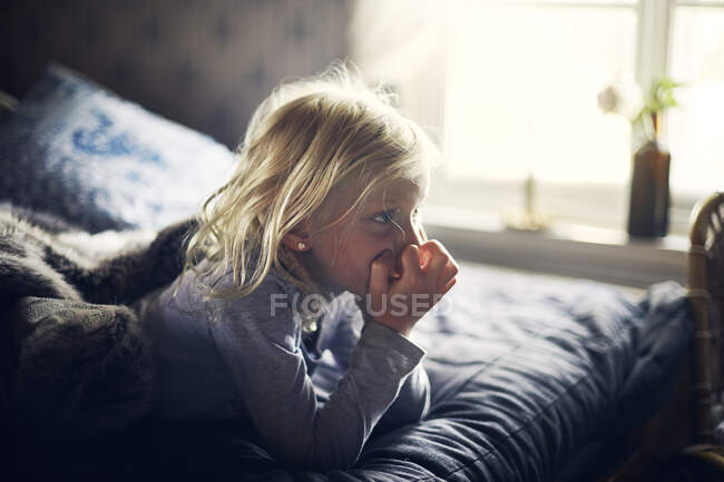 Ragazza sdraiata sul letto e guardando da parte a casa — Foto stock