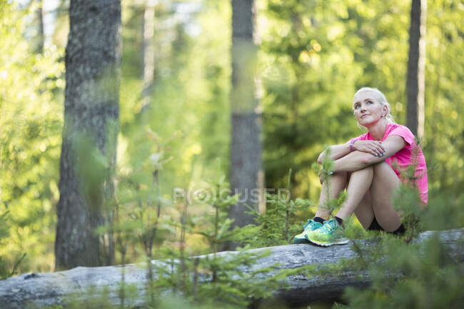 Femme assise sur une bûche dans la forêt — Photo de stock