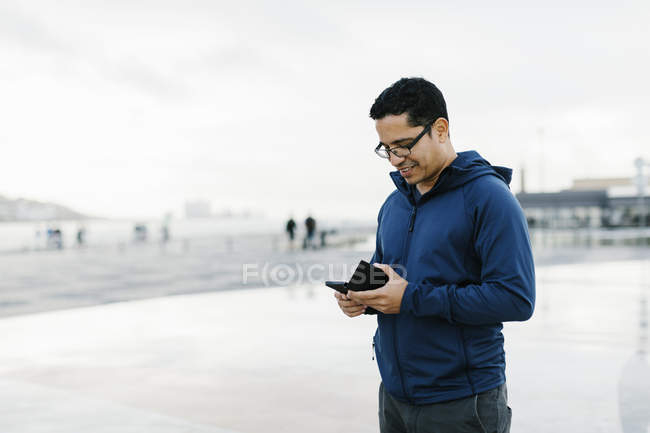 Homem usando telefone inteligente na praça da cidade — Fotografia de Stock