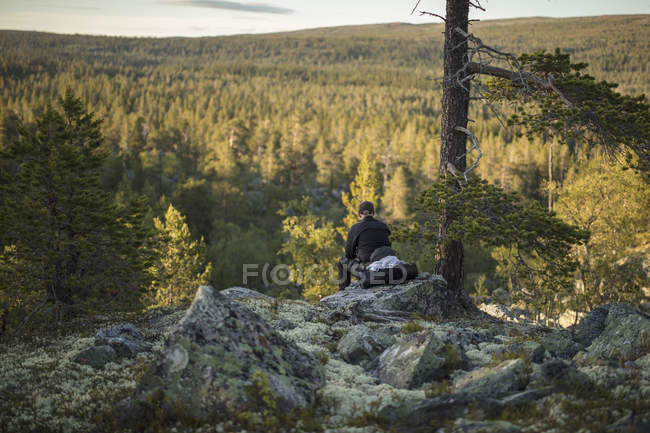 Человек сидит на скале в природном заповеднике Тофсингдален в Швеции — стоковое фото