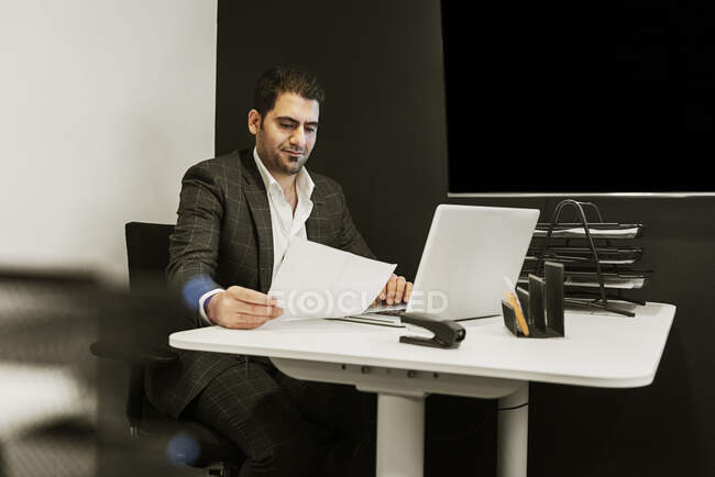 Junger Mann sitzt am Schreibtisch und arbeitet mit Laptop im Büro — Stockfoto