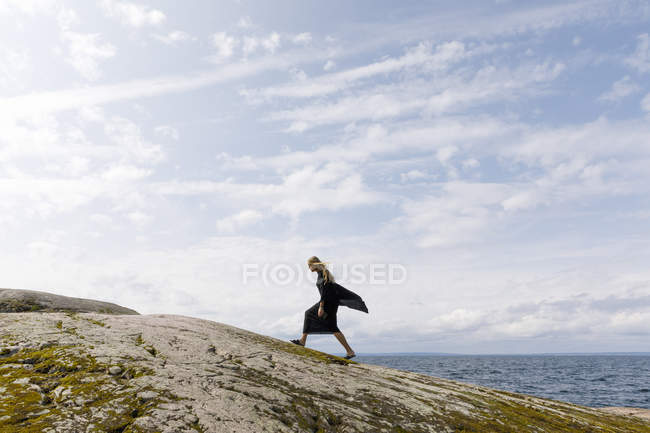Женщина в черной ходьбе по скале — стоковое фото