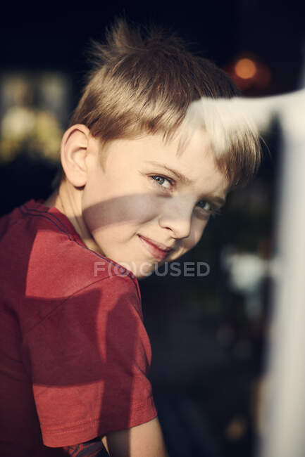 Мальчик смотрит в камеру из окна — стоковое фото