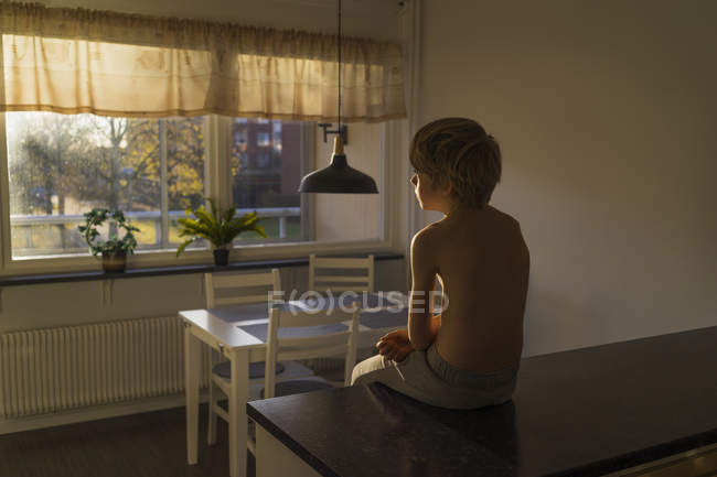 Хлопчик сидить на кухонній лавці, вибірковий фокус — стокове фото