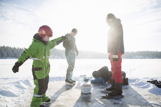 Garçon et hommes avec barbecue sur le lac gelé de Drang en Hautes-terres, Suède — Photo de stock