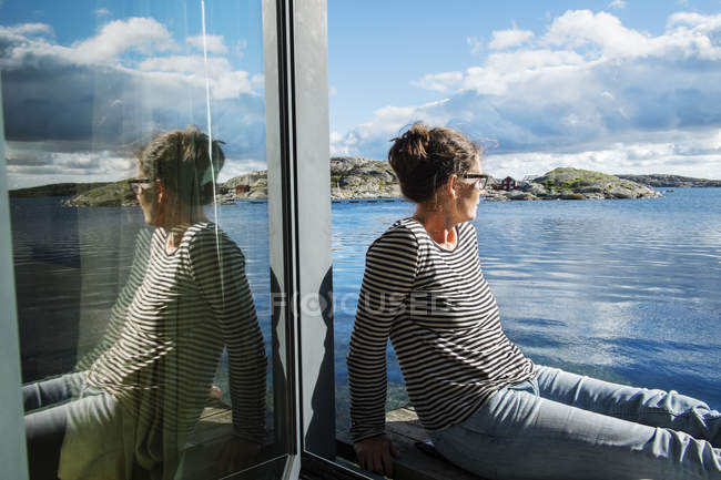 Зрелая женщина, сидящая на балконе над морем, избирательный фокус — стоковое фото