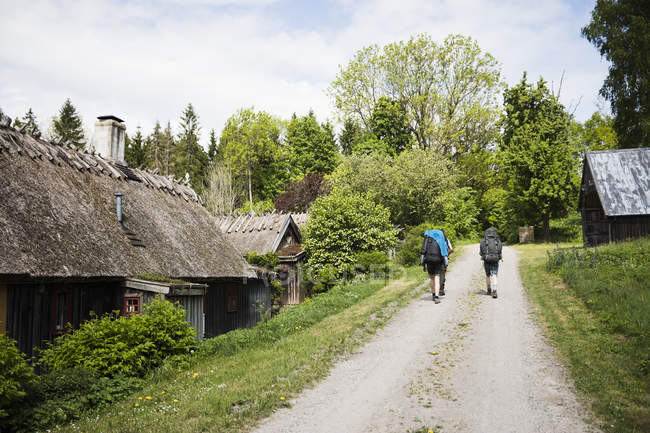 Men hiking on rural road by houses — Stock Photo