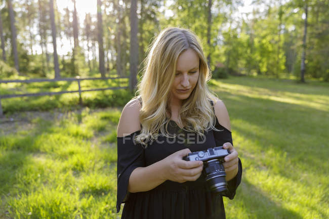 Young woman holding camera in field — Stock Photo