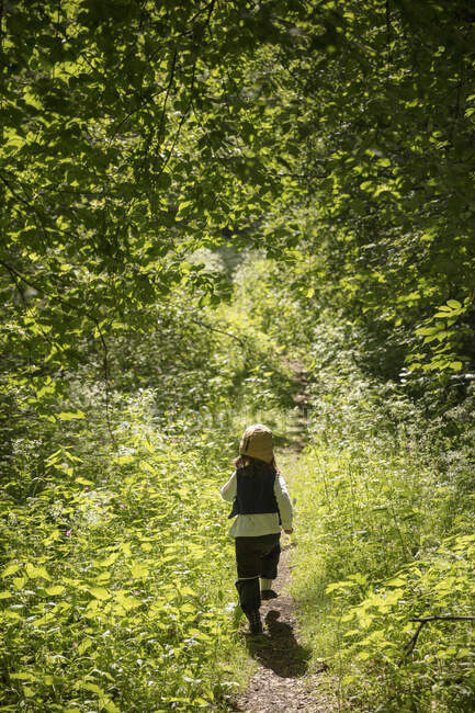 Girl running by green trees, back view — Stock Photo