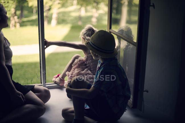 Niños saliendo por la ventana, enfoque selectivo - foto de stock
