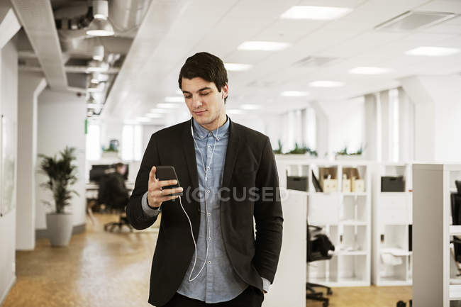 Молодой человек использует смартфон в офисе — стоковое фото