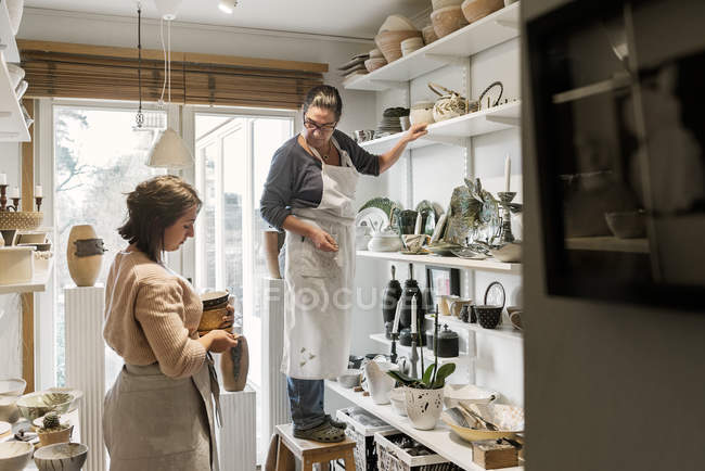 Mujeres por estantes de cerámica, enfoque selectivo - foto de stock