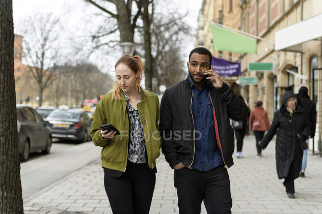 Пара, использующая смартфоны на тротуаре, избирательный фокус — стоковое фото