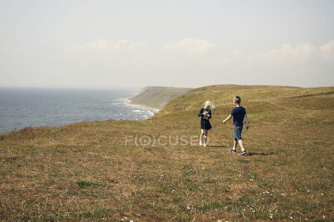 Niño y niña en la colina cerca del mar - foto de stock