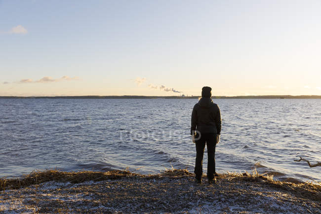 Femme mûre debout à côté du lac Glan au coucher du soleil en Suède — Photo de stock