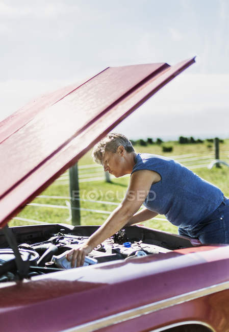 Reife Frau kontrolliert Auto unter Motorhaube — Stockfoto