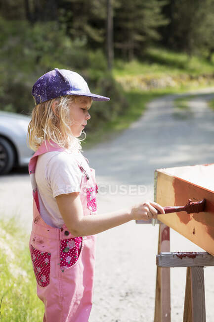 Chica pintura de madera al aire libre, vista lateral - foto de stock