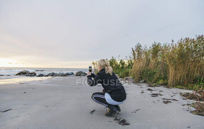 Donna scattare foto sulla spiaggia — Foto stock