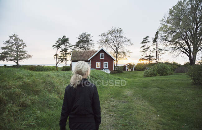 Жінка в полі за будинком, вид ззаду — стокове фото