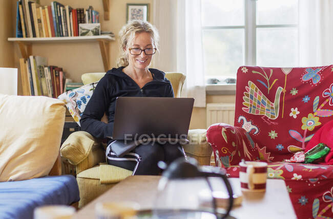 Woman using laptop on armchair — Stock Photo