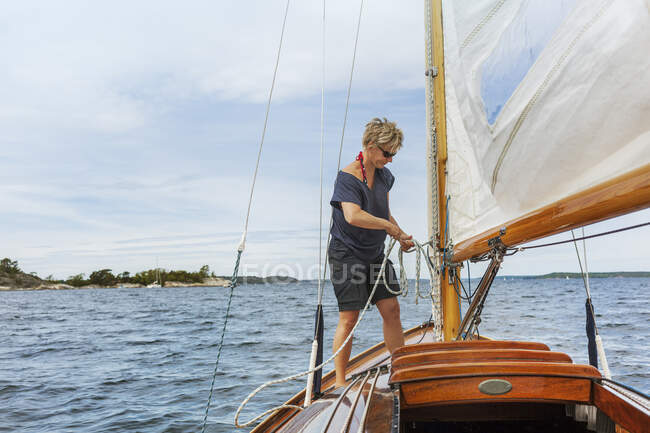 Mujer adulta que navega en su yate - foto de stock
