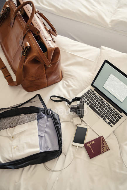 Computer portatile, borsa e cose diverse a letto, messa a fuoco selettiva — Foto stock