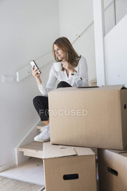 Женщина сидит на лестнице и использует смартфон — стоковое фото