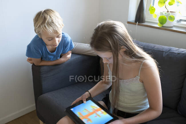 Menino e menina olhando para um tablet PC em casa — Fotografia de Stock