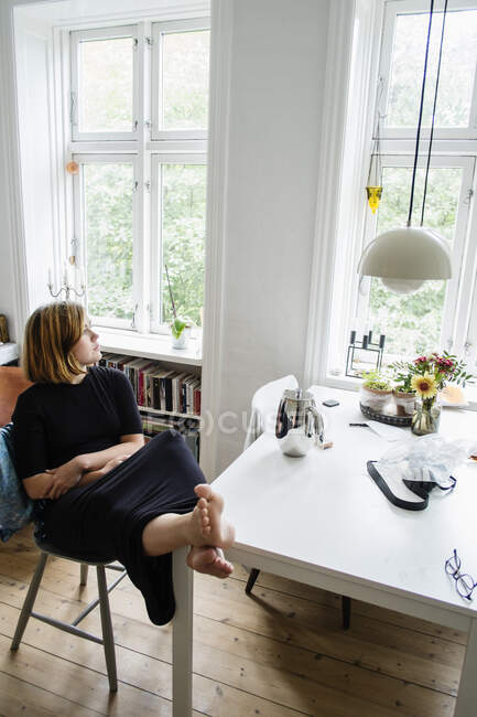 Молода жінка сидить з ногами в квартирі — стокове фото