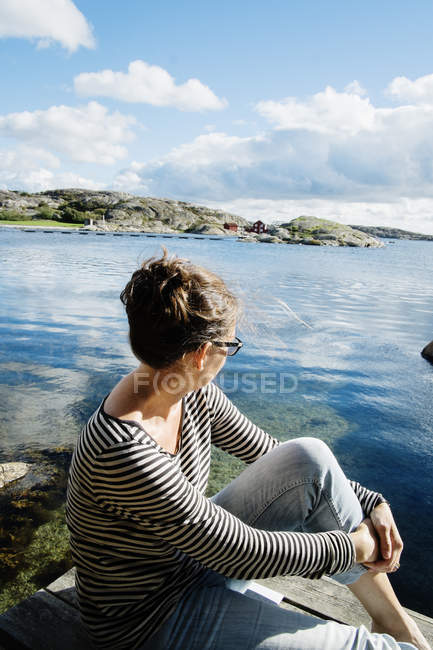 Зрелая женщина сидит на балконе над морем — стоковое фото
