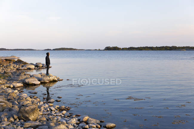 Hombre de pie sobre rocas cerca del mar en el archipiélago de Santa Anna, Suecia. - foto de stock