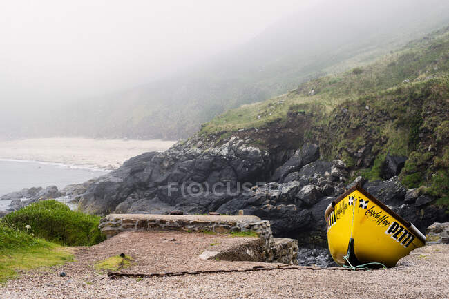 Gelbes Boot neben felsigen Klippen an der Küste von Cornwall, England — Stockfoto