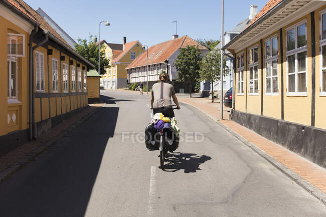 Uomo in bicicletta per strada al giorno di sole, indietro vista — Foto stock