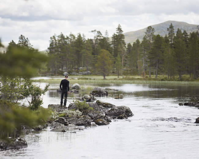 Uomo in piedi lungo il fiume, attenzione selettiva — Foto stock