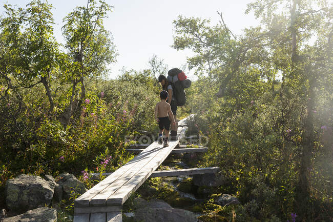Randonnée avec la mère et le fils sur un pont en bois dans le parc national de Fulufjallet, Suède — Photo de stock