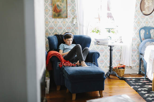 Boy wearing headphones on armchair — Stock Photo