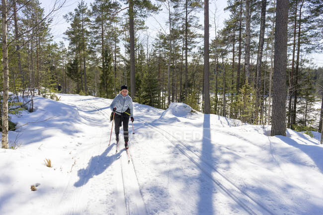 Жінка середнього віку катається на лижах у зимовому лісі — стокове фото