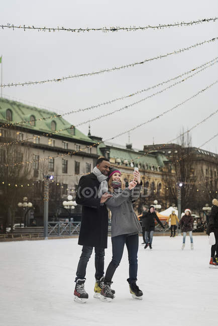 Casal tomando selfie enquanto patinação no gelo, foco seletivo — Fotografia de Stock
