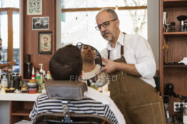 Peluquero mostrando joven corte de pelo, enfoque selectivo - foto de stock