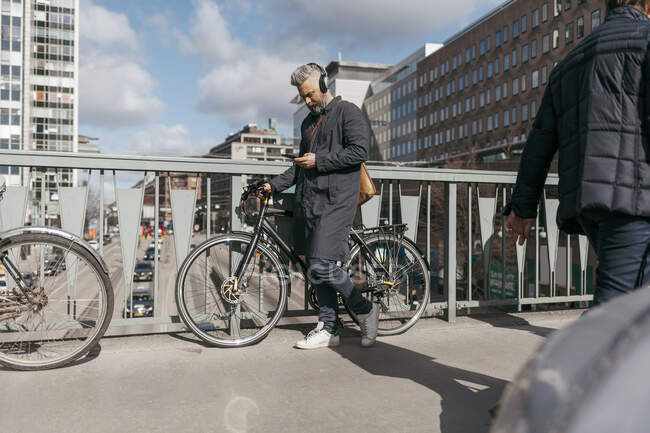 Чоловік з велосипедом і смартфоном на вулиці — стокове фото