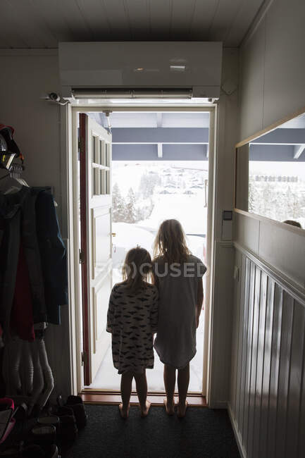 Sisters standing at front door - foto de stock